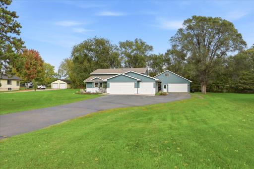 Welcoming exterior situated on a spacious lot with mature trees, an expansive driveway, attached three-car garage, and impressive detached garage for additional parking and storage.