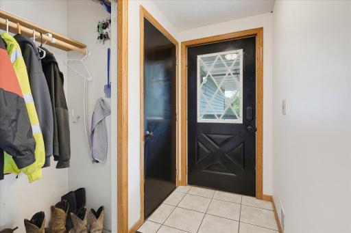 Functional front entry with tile flooring, access to the garage, convenient coat storage, and warm natural wood trim.