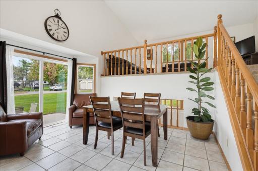 Bright dining area features a vaulted ceiling, tile flooring, and sliding glass doors providing direct access to the side patio.