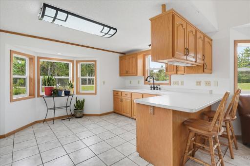 The kitchen offers abundant oak cabinetry, generous counter space, a peninsula with casual seating, tile flooring, and a charming bay-window area.