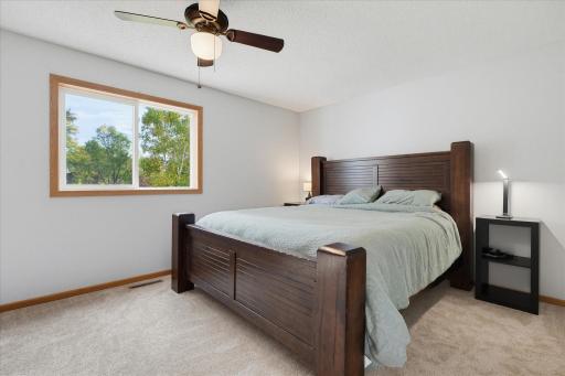 Spacious primary bedroom features a vaulted ceiling, new carpet, ceiling fan, and updated window.