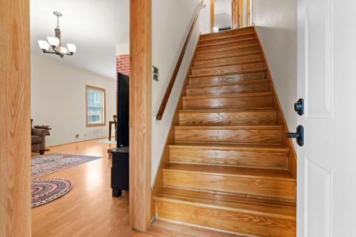 Wide solid wood staircase leading to two upper level bedrooms and a bath