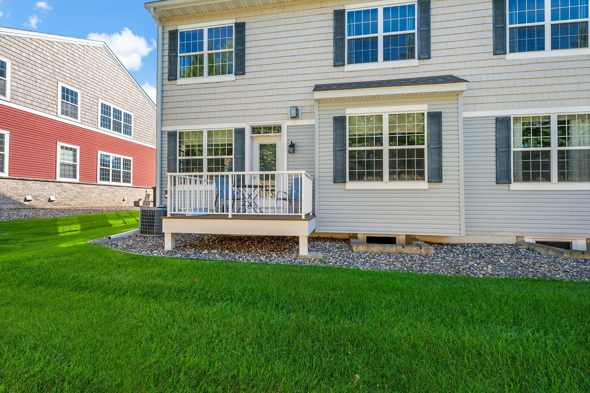 Rear exterior of this Lakeville townhome with private deck and green space.