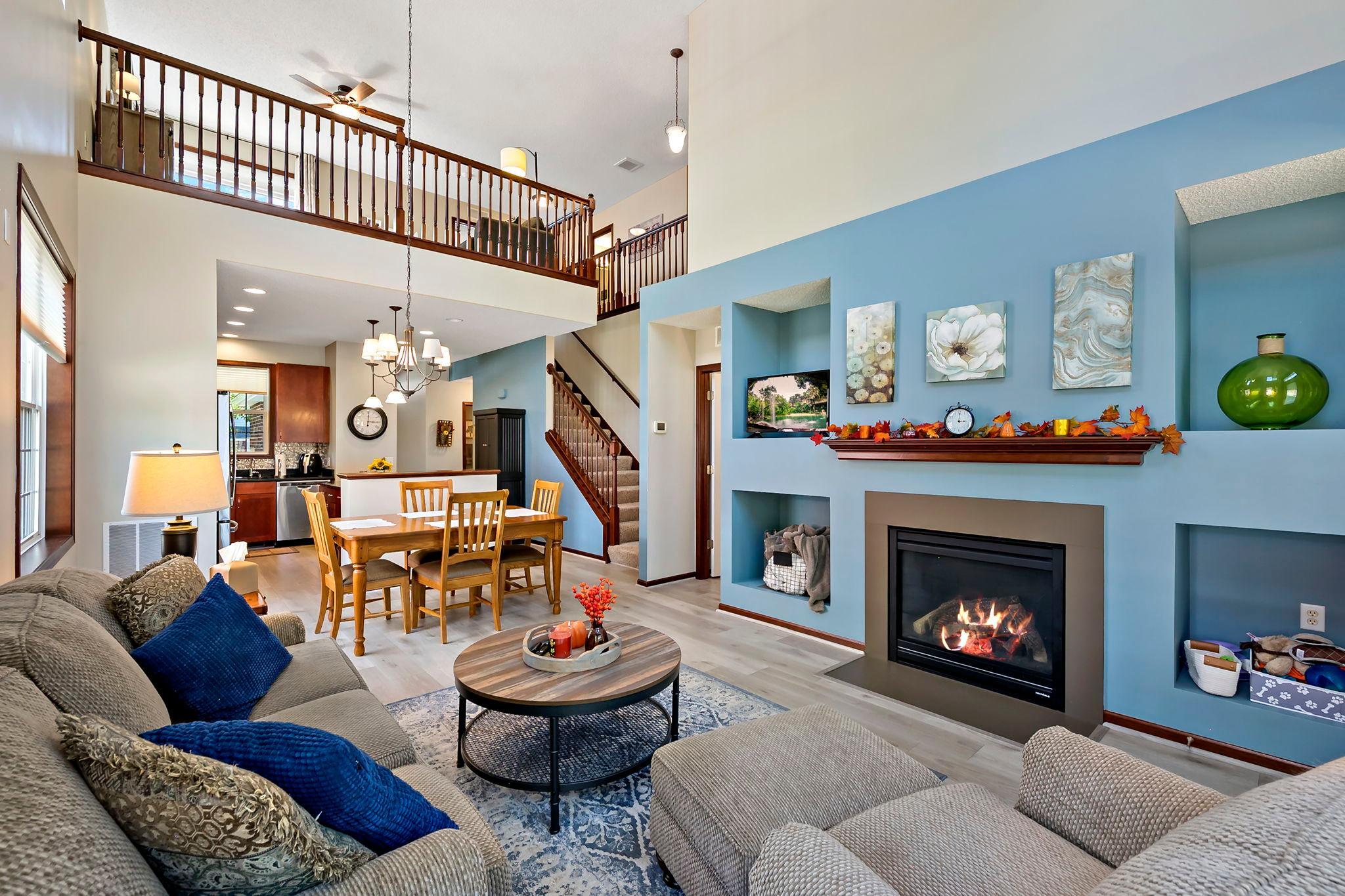 Two-story living space with fireplace, upper-level loft and open staircase.