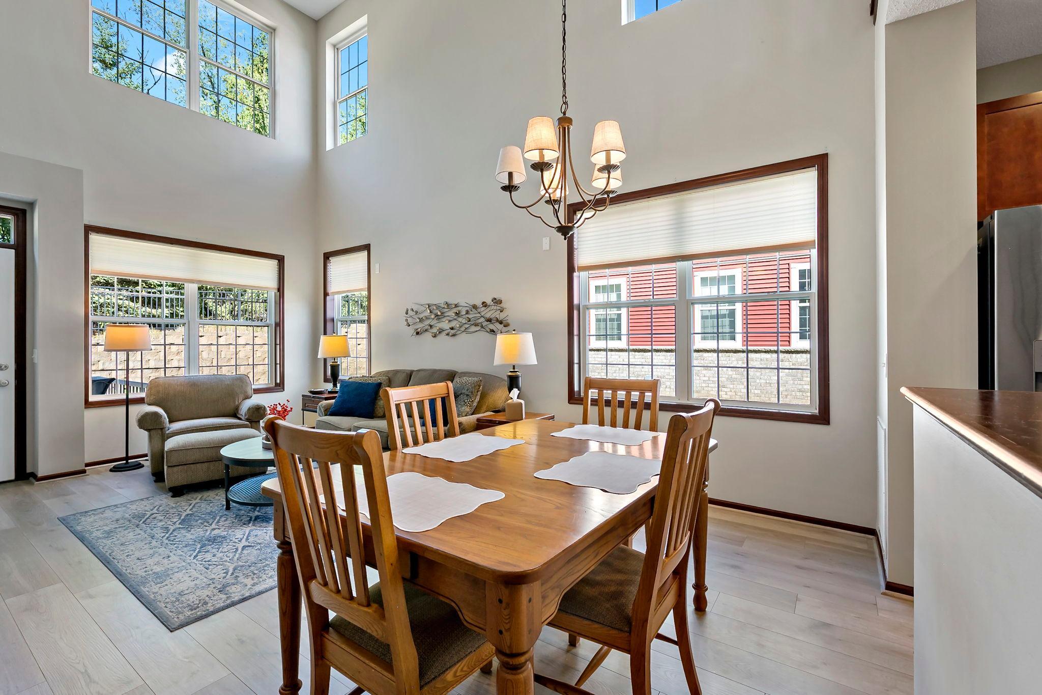 Bright dining and living area with dramatic vaulted ceilings and abundant windows.