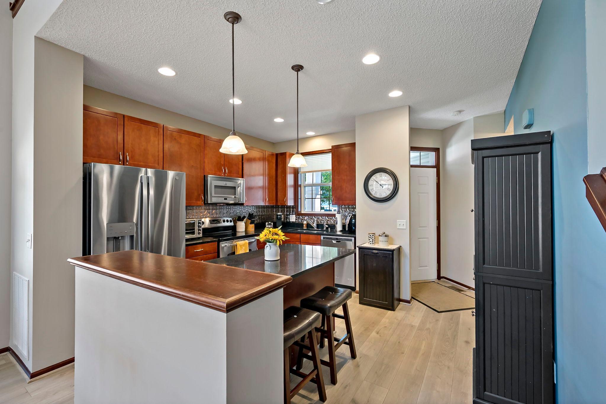 Stainless steel appliances, rich wood cabinetry and decorative kitchen backsplash.