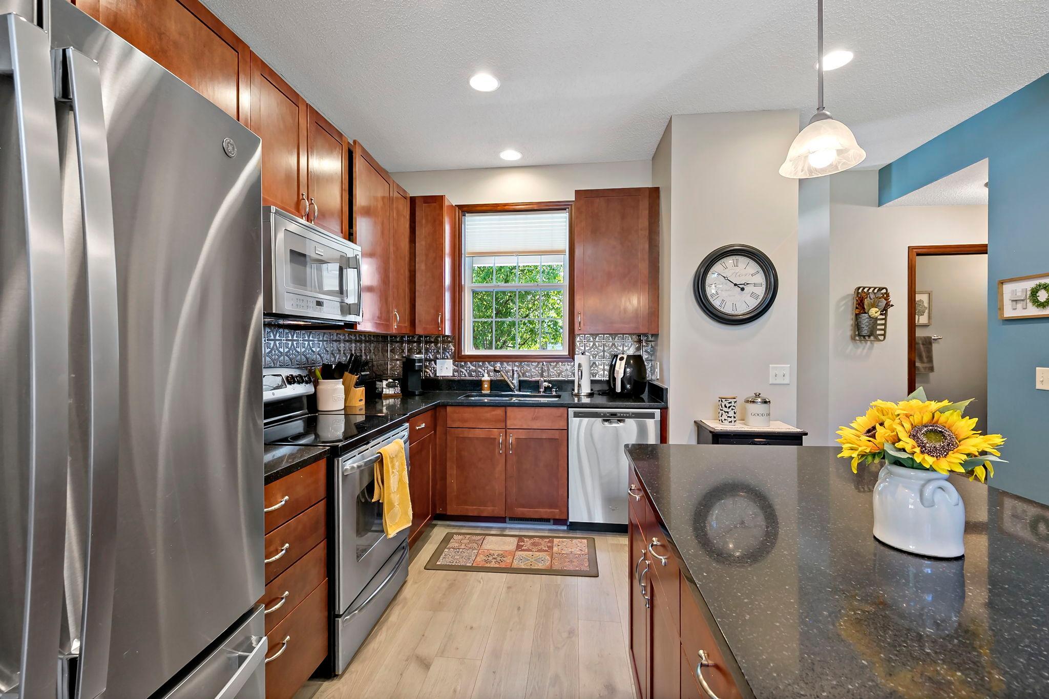 Stainless steel appliances, rich wood cabinetry and decorative kitchen backsplash.