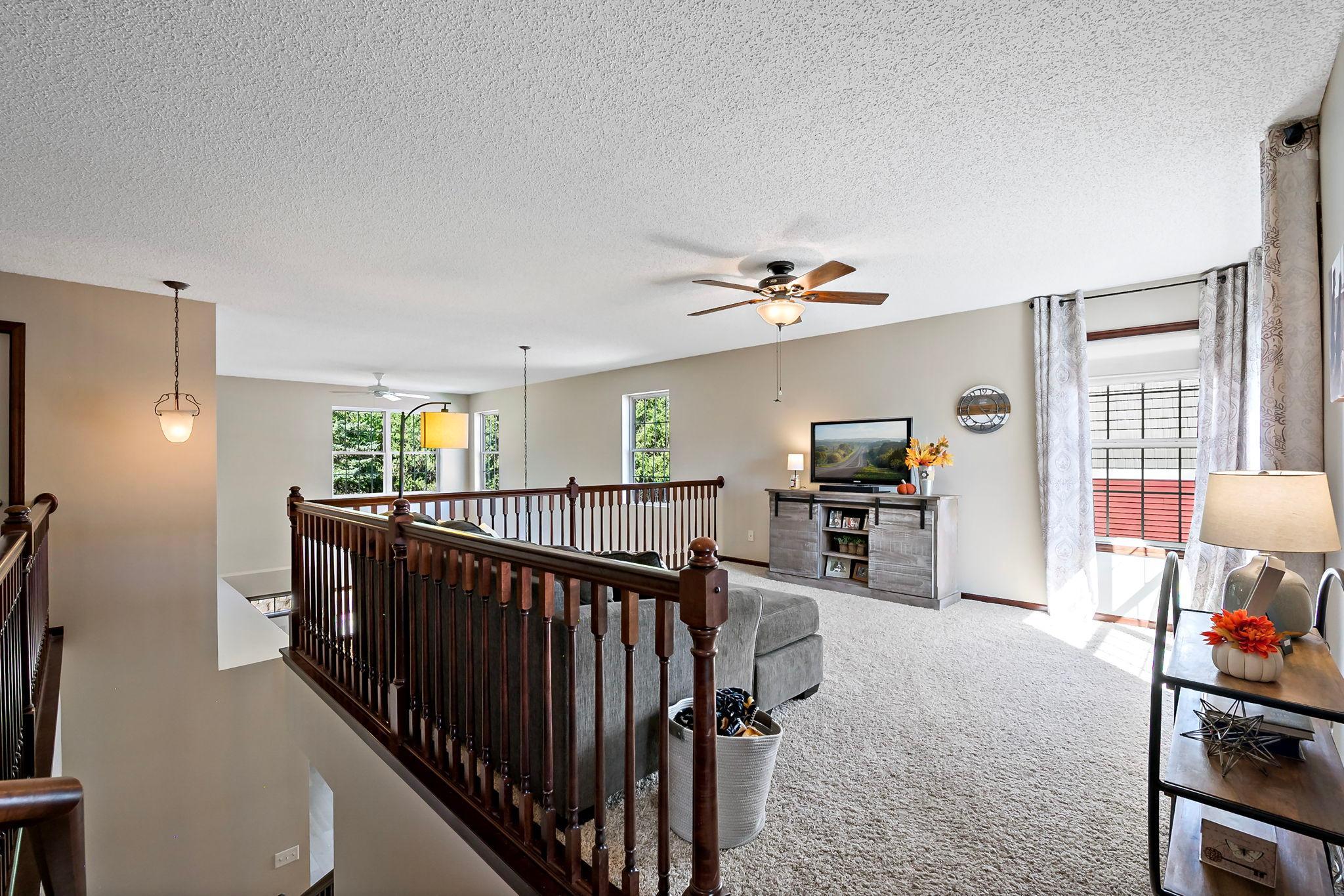 Two-story living space with fireplace, upper-level loft and open staircase.
