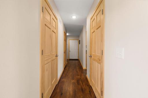 The main floor hallway with bathroom on the immediate left and a utility closet on the left, garage access door in the center and access to the crawl space beyond the last closed door.