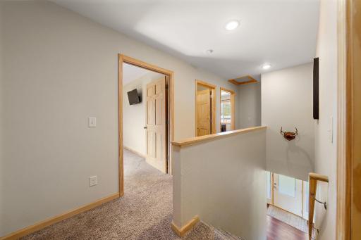 Standing in the stairwell of the upper level with the front door of the home visible down the staircase on the right.