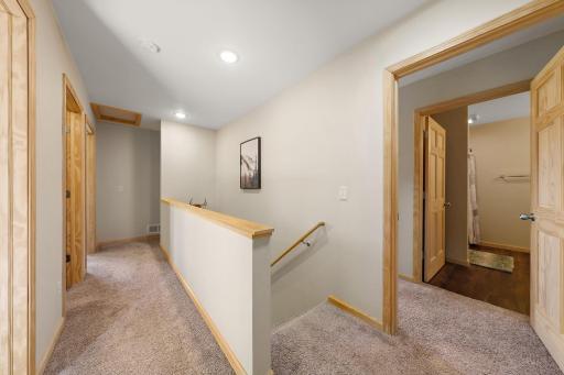 The primary bedroom with the en suite bathroom is visible through the open door on the right. The laundry closet is located to the right of the primary bedroom at the top of the stairs.