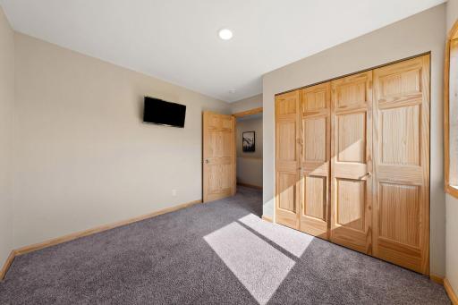A view of the third bedroom with the hallway and staircase visible through the open doorway.