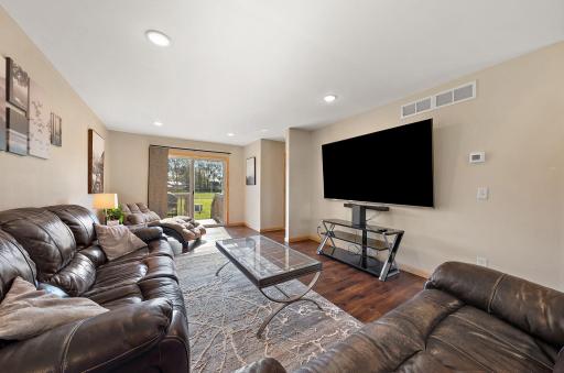 A view of the living room from the corner with the backyard patio door and stoop visible beyond.