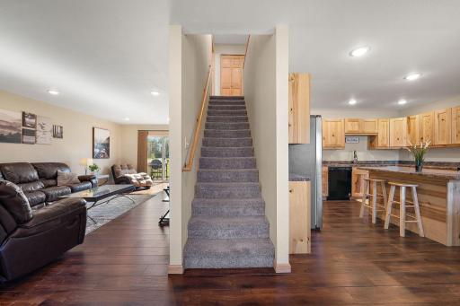 Standing in front of the front door from the porch with the main floor living area on the left, stairs leading to the upper level in the center and the kitchen and dining area on the right. Laundry closet located at the top of the stairs.