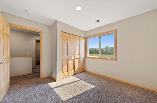 The third bedroom is located near the primary bedroom and the stair case. The window has a view of the backyard.