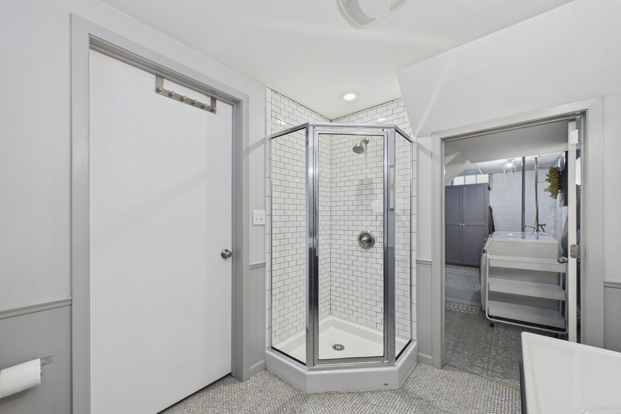 The lower level bathroom has a tiled shower. The doorway is another entrance to the utility room.