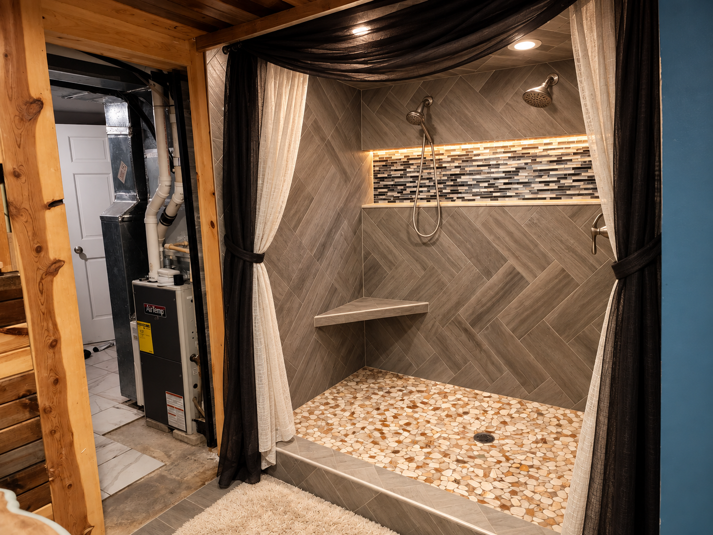 A standout primary ensuite featuring a spacious walk-in shower with dual shower heads, herringbone tile, built-in bench, pebble tile floor and illuminated mosaic accent niche.
