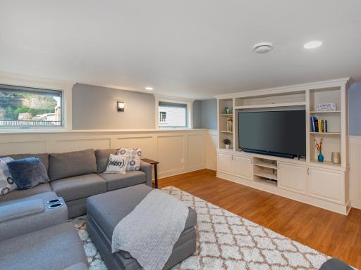 The lower-level family room features classic wainscoting and custom built-ins, creating a warm and inviting gathering space.