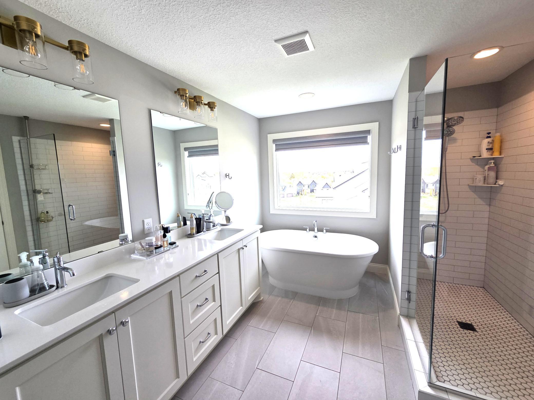 Luxurious primary bathroom with soaking tub, custom tile work, and double vanity.
