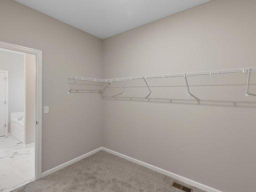 PHOTO OF A DIFFERENT HOME WITH SIMILAR PLAN. FINISHES MAY VARY. Primary Suite Walk-in Closet.