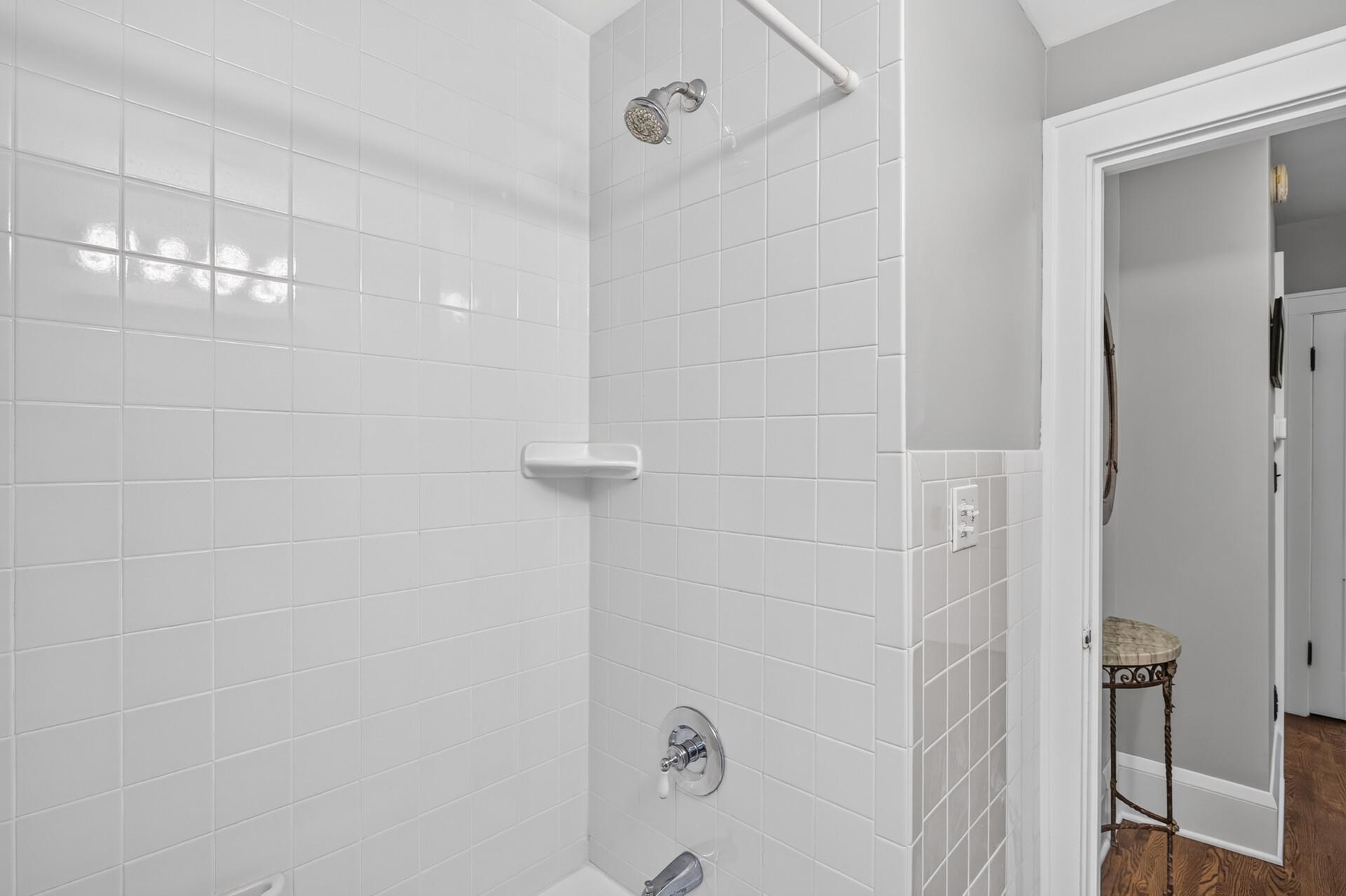 Main-level full bath with a tub and a tiled shower surround.