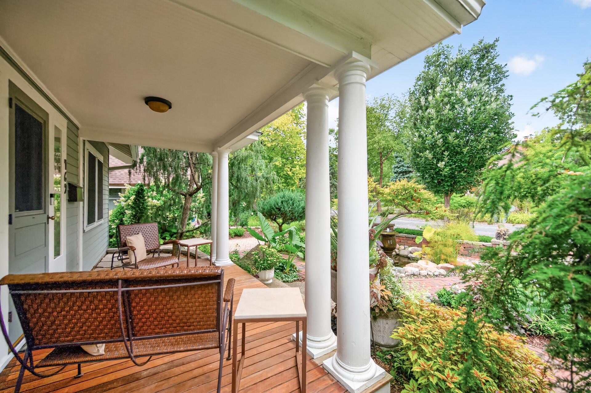 Another view of the expansive covered porch, showcasing the wood floors, beams and lush front gardens.