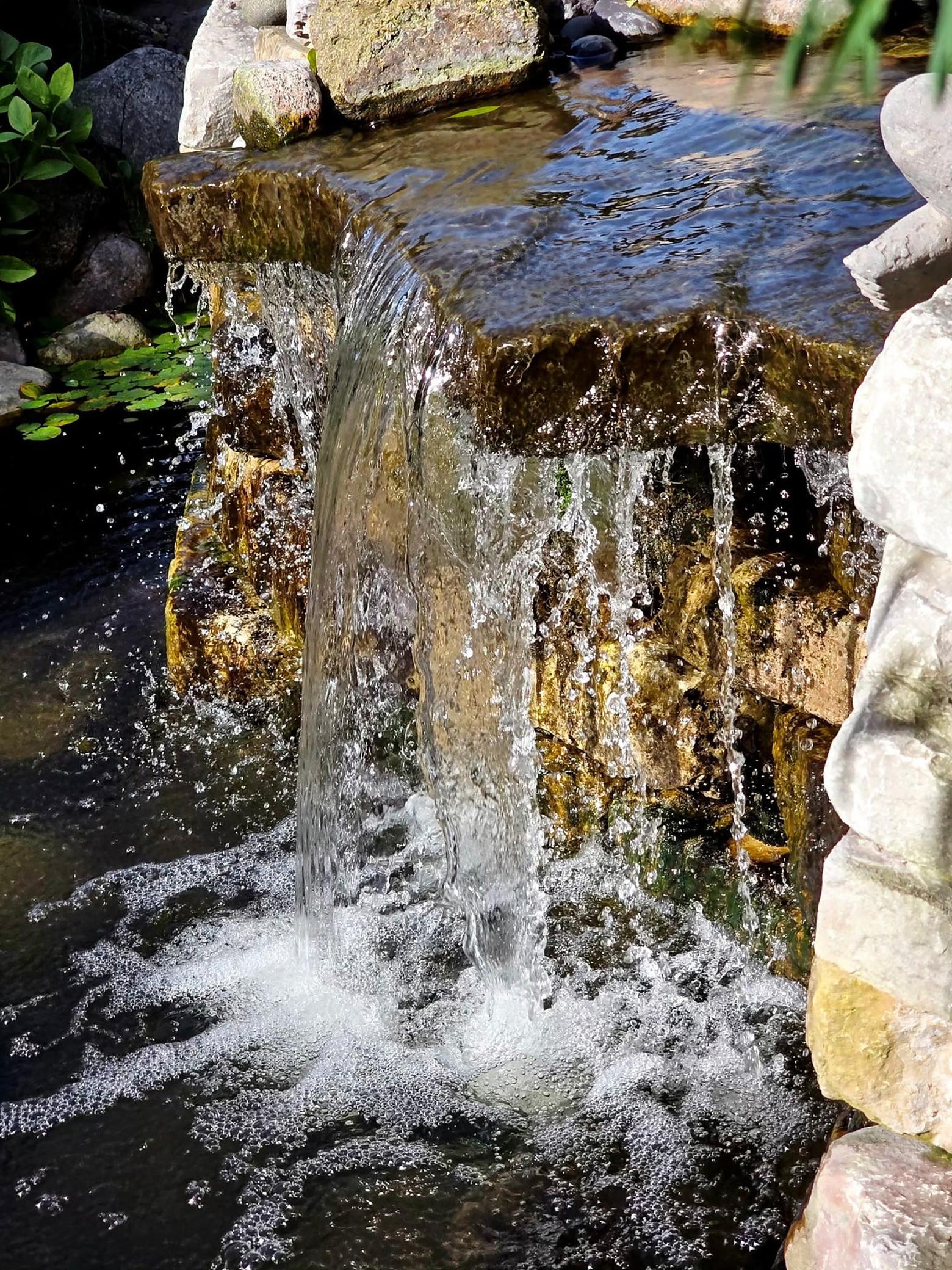Close-up of the cascading garden waterfall, highlighting the movement and texture of this beautiful backyard water feature.