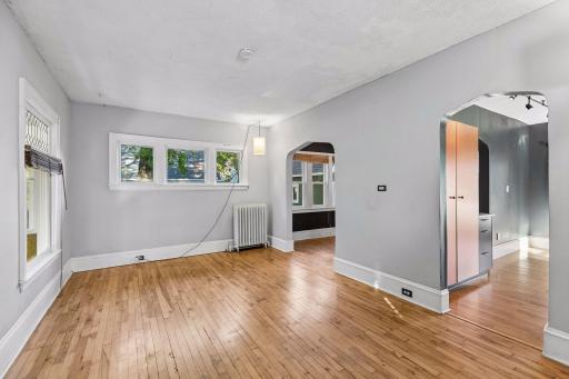 Hardwood flooring and an abundance of windows bring warmth and natural light to the living room, which flows easily into the kitchen and formal dining space.