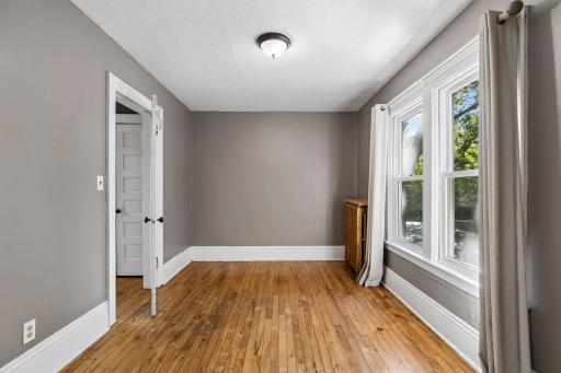 The first of two upper level bedrooms provides a comfortable space with hardwood flooring, two windows, and overhead lighting.