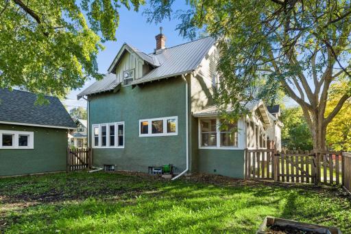 Another look at the home from the fenced in yard, with durable stucco siding and a metal roof adding lasting appeal.