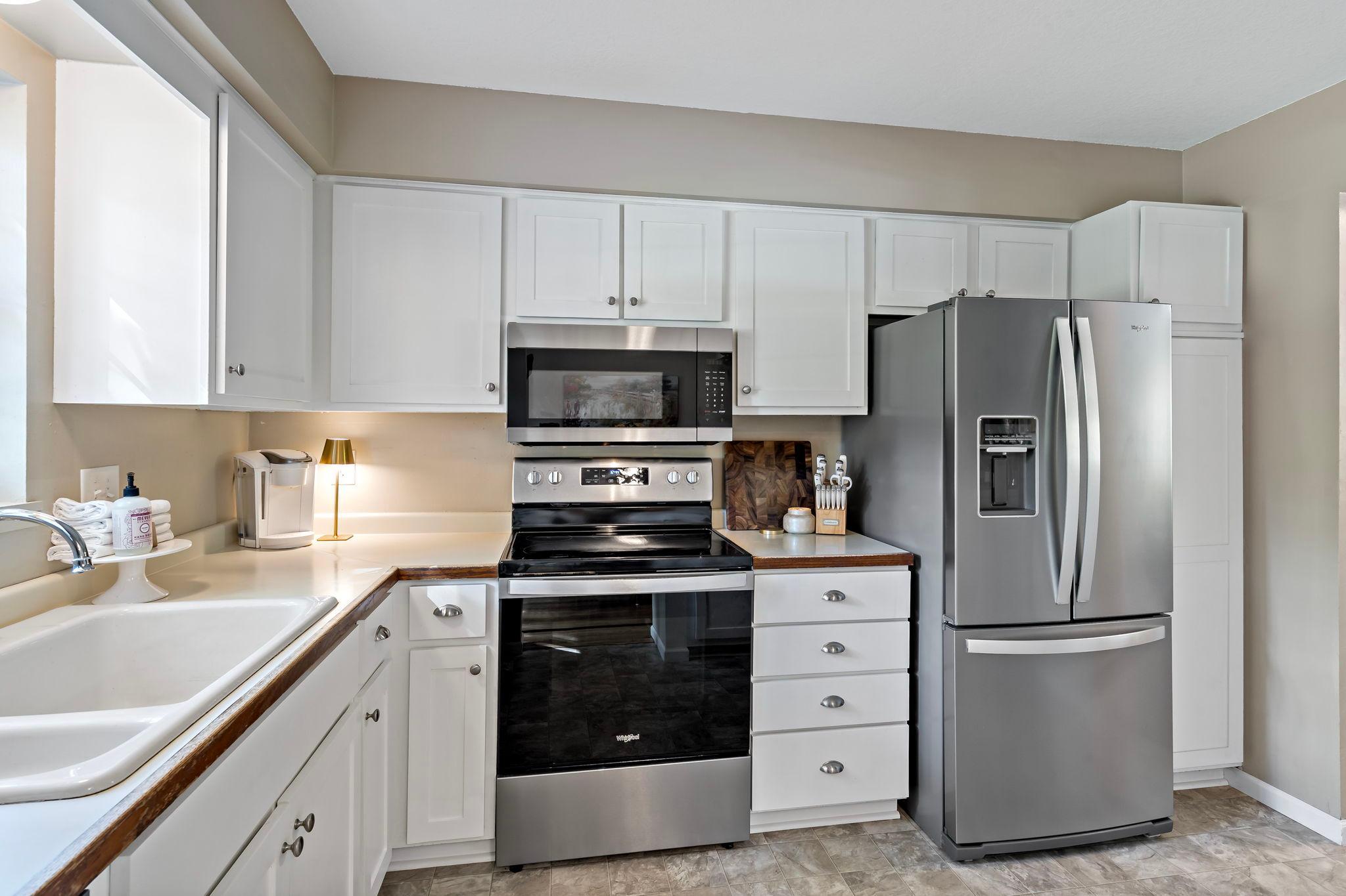 A full suite of new stainless steel appliances, including a French-door refrigerator, electric range, microwave, and dishwasher, brings a fresh, modern touch to the kitchen. Additional floor-to-ceiling cabinetry provides valuable storage.