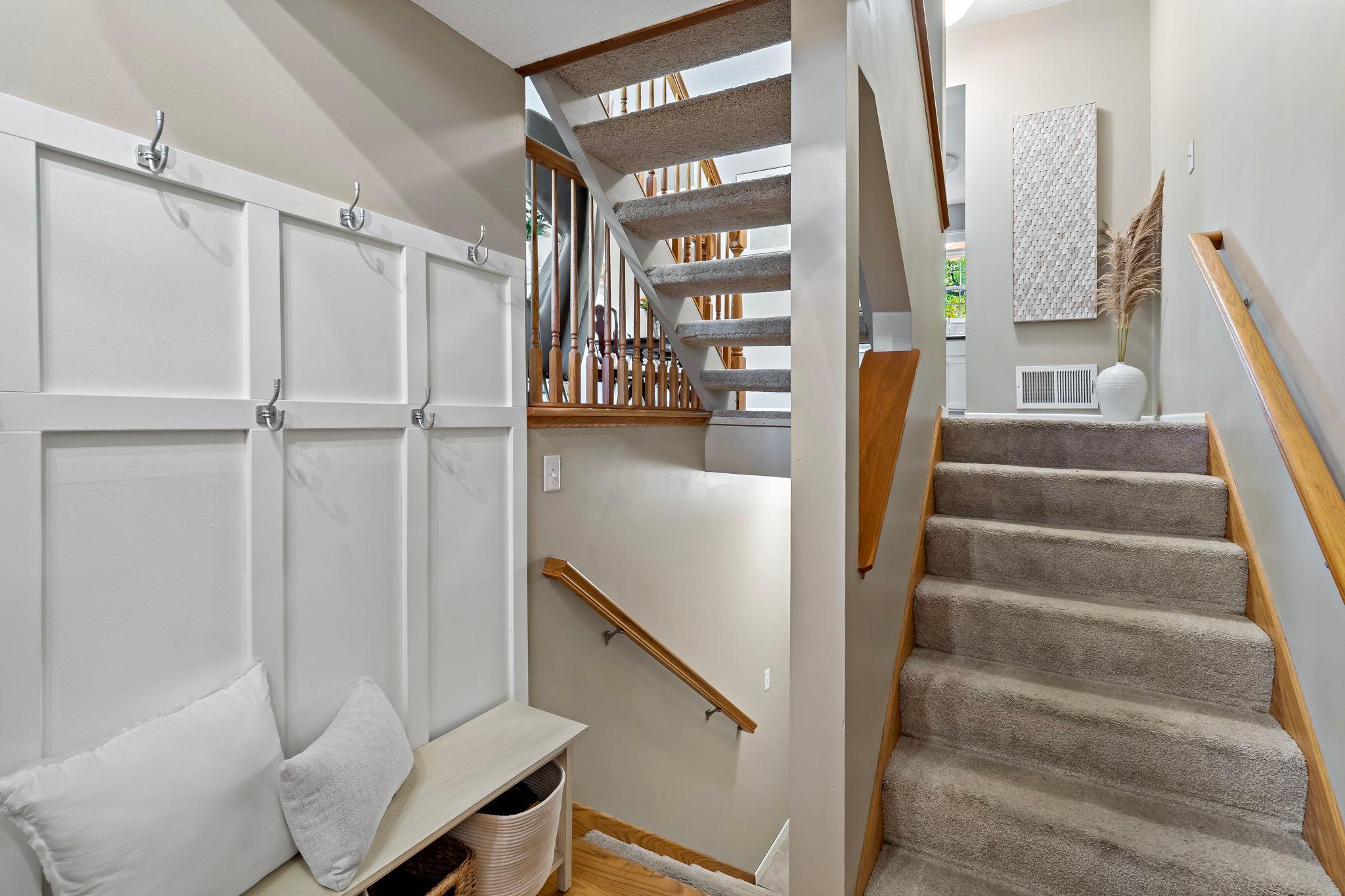 A welcoming entry features hardwood floors & a convenient zone with hooks & space for everyday essentials. Head downstairs for direct access to the attached garage, while the stairs up lead to the home’s main living areas.