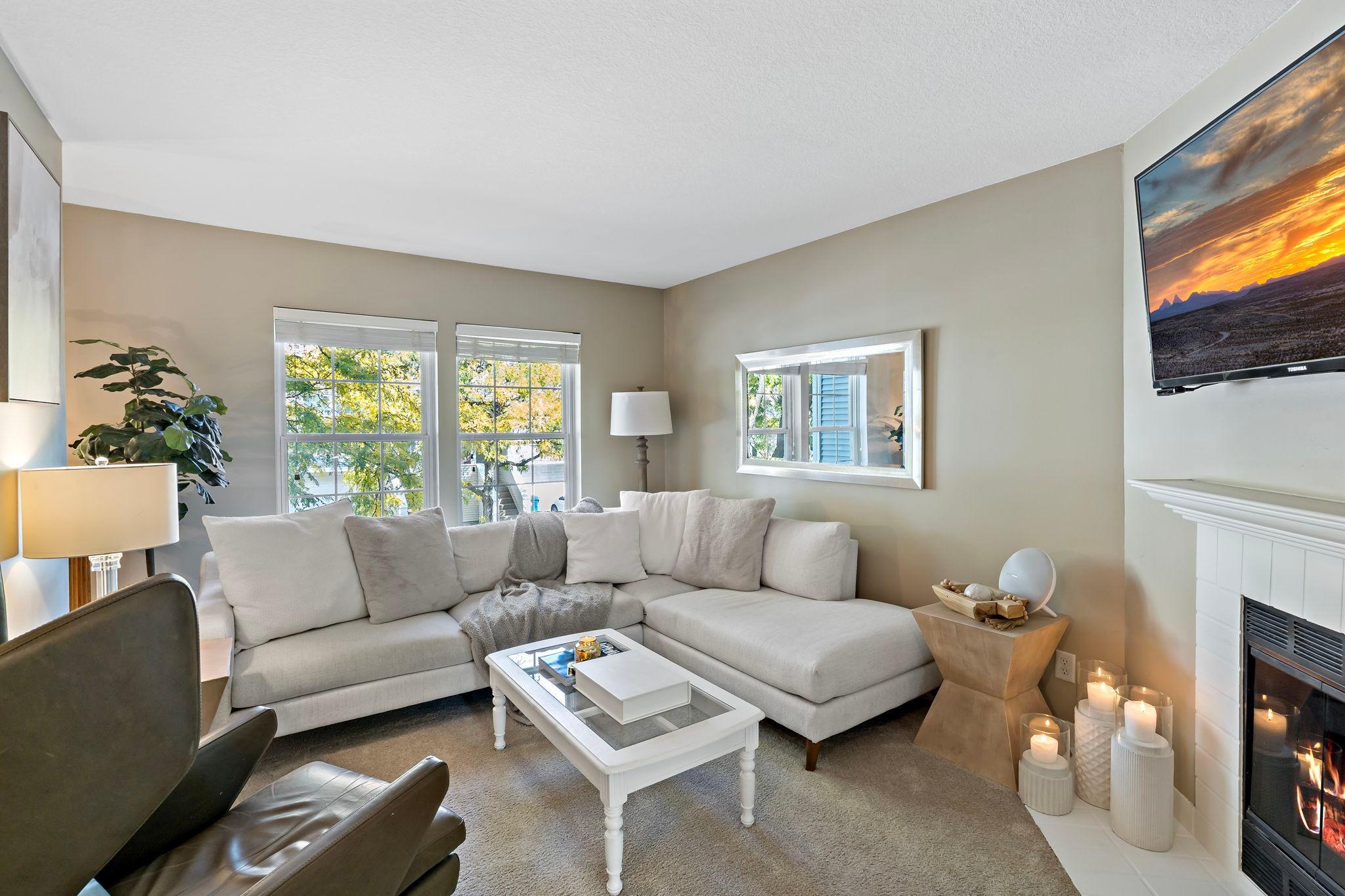 This inviting living room features 8-foot ceilings, soft carpeting, and two large windows. The natural light from the windows creates a warm and comfortable setting for relaxing or entertaining.