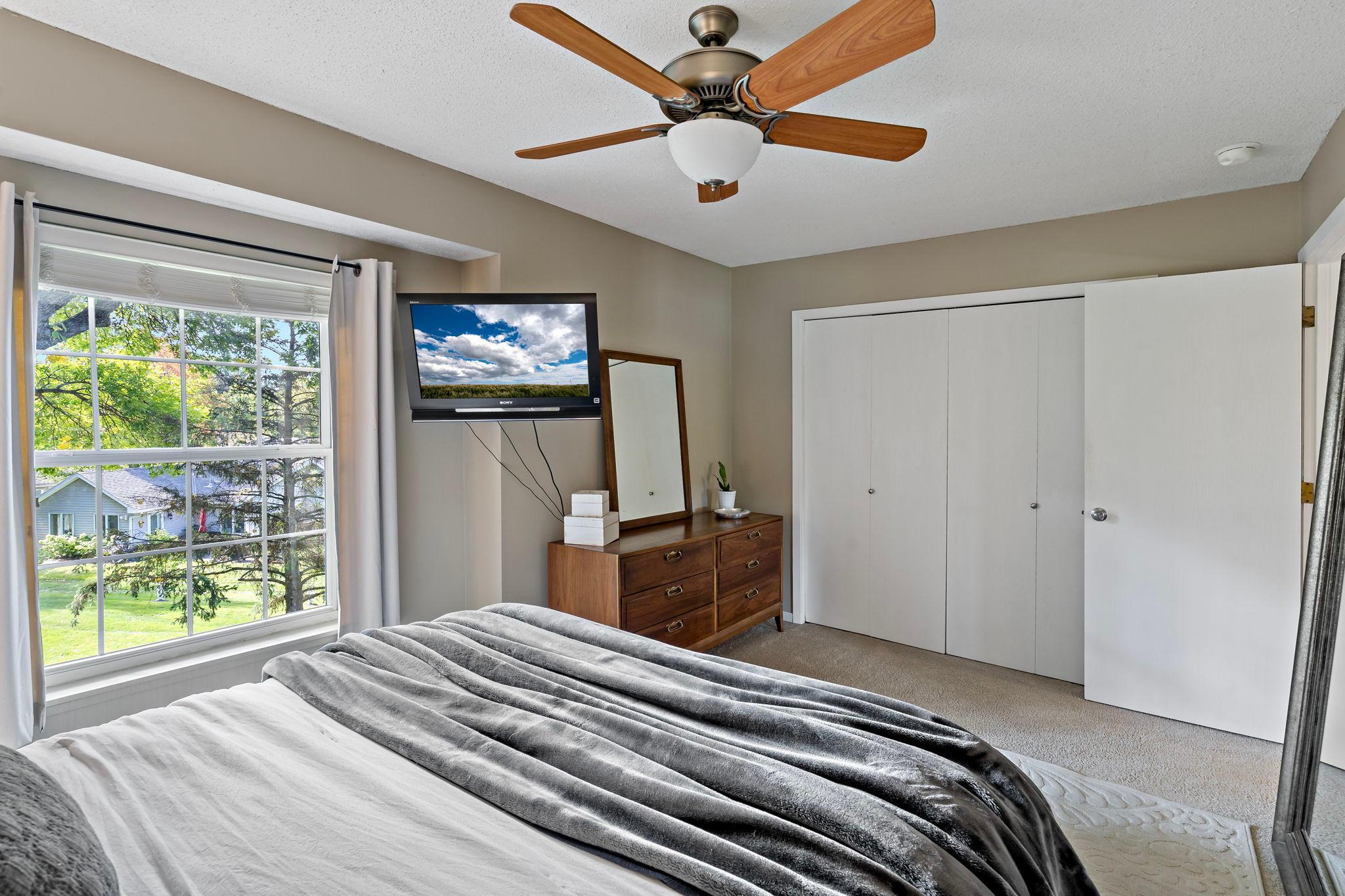 A second view highlights the impressive wall-length closet, providing abundant storage while leaving plenty of usable bedroom space. The ceiling fan with integrated lighting adds comfort and convenience year-round.