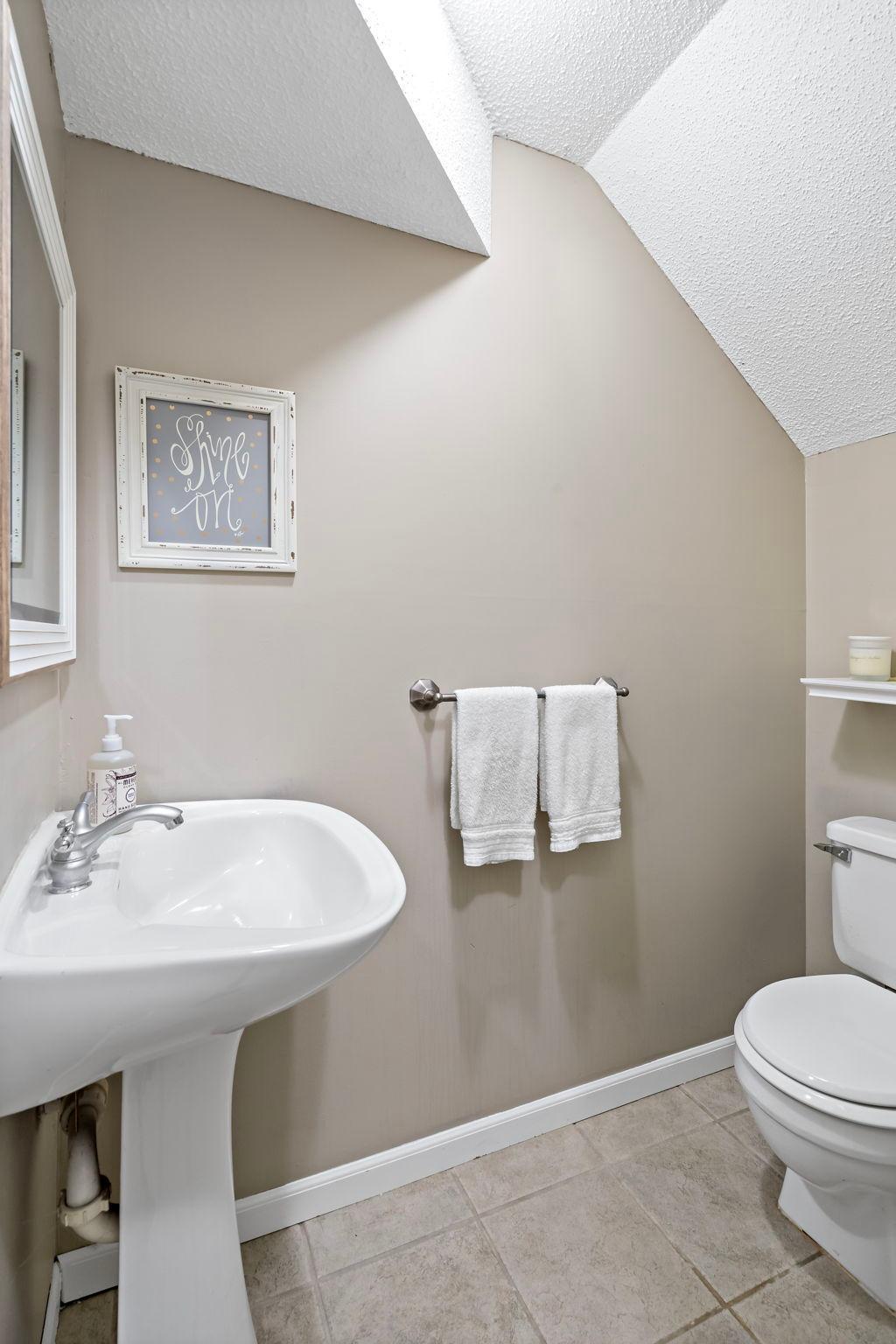 Conveniently located just off the garage entry, the lower-level half bath features tile flooring and a pedestal sink, offering added functionality for both residents and guests.
