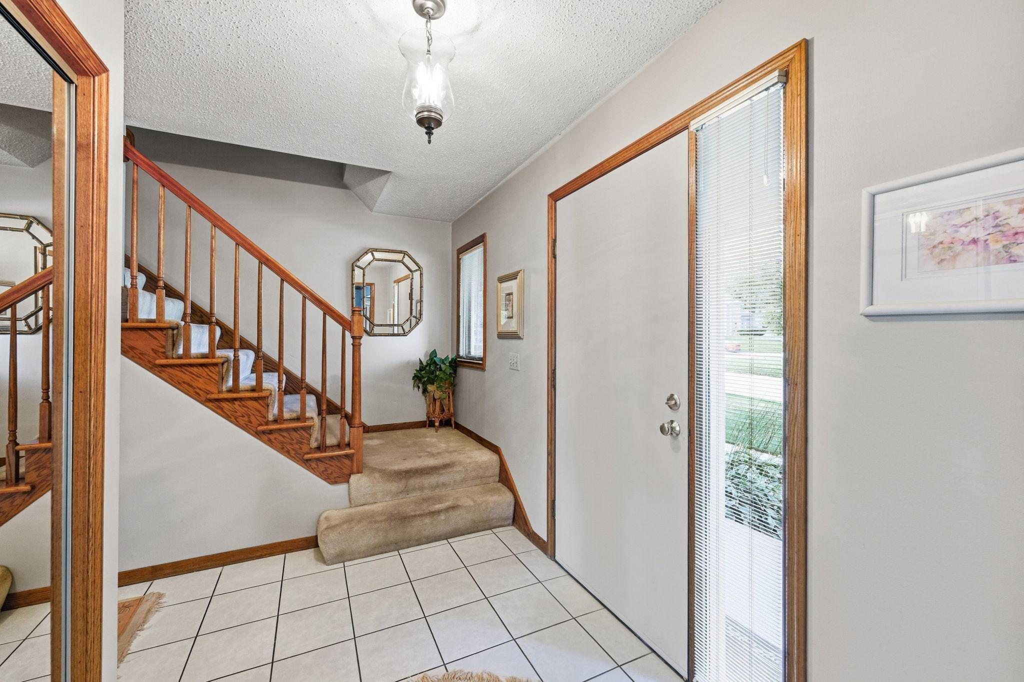 Entry featuring while ceramic tiles and the stairway to the upper level