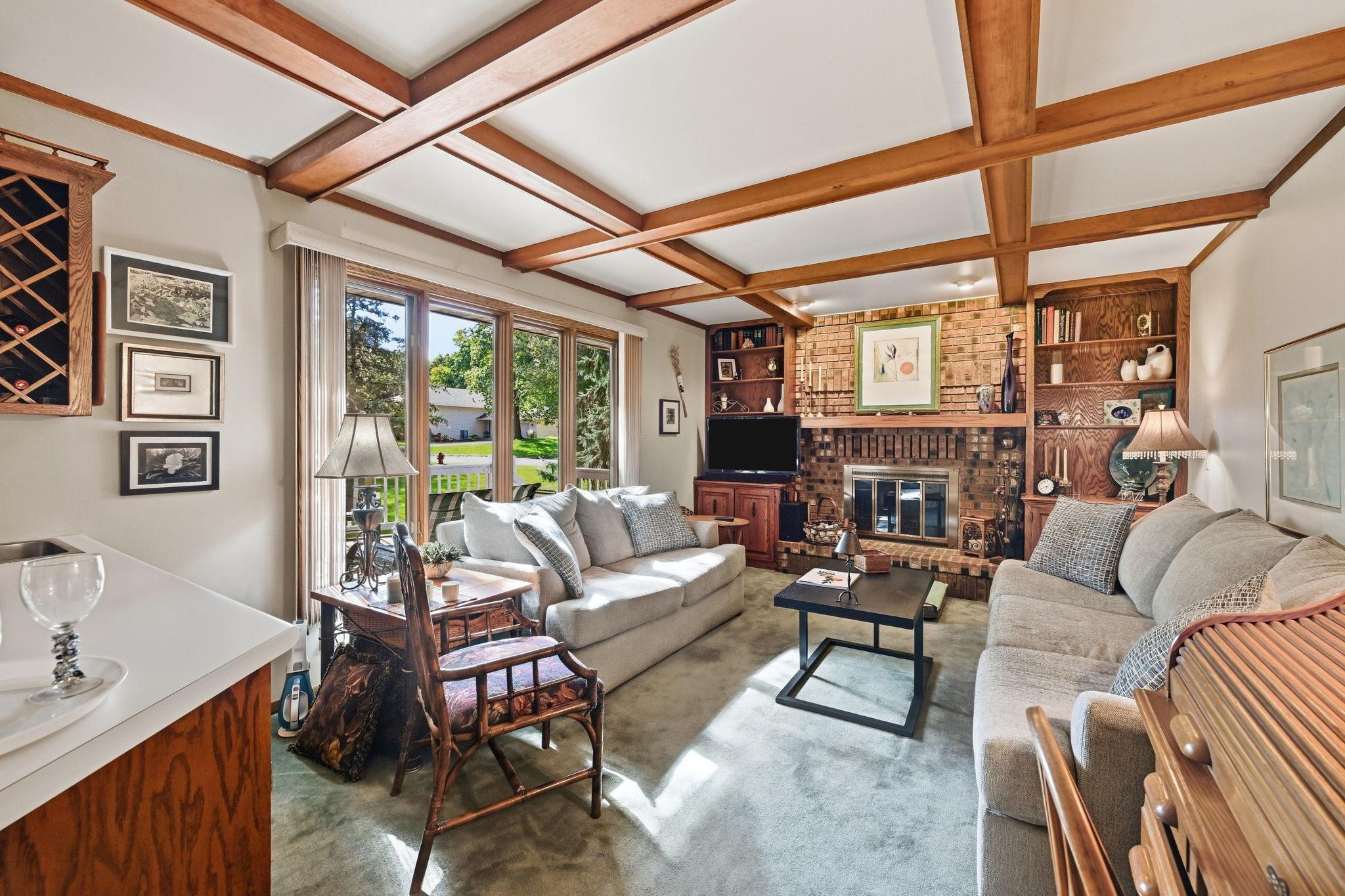 The family room featuring wine rack, wet bar, brick fireplace and handsome coffered ceiling