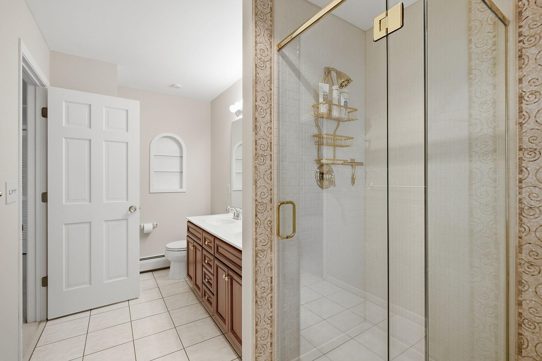Primary bathroom features double sinks, tile flooring, and a walk-in shower