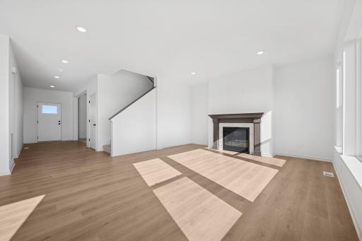 A cozy fireplace and open layout make this living room the perfect gathering space. Modern finishes and abundant natural light create a warm, welcoming atmosphere. Home under construction, photo of similar home, selections vary.