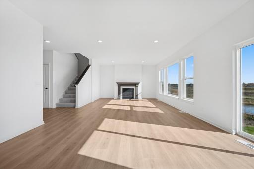 A cozy fireplace and open layout make this living room the perfect gathering space. Modern finishes and abundant natural light create a warm, welcoming atmosphere. Home under construction, photo of similar home, selections vary.