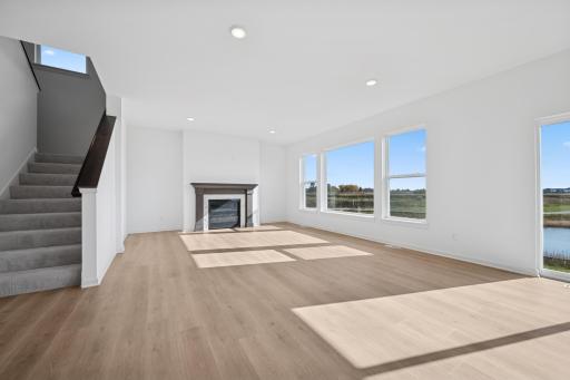 A cozy fireplace and open layout make this living room the perfect gathering space. Modern finishes and abundant natural light create a warm, welcoming atmosphere. Home under construction, photo of similar home, selections vary.