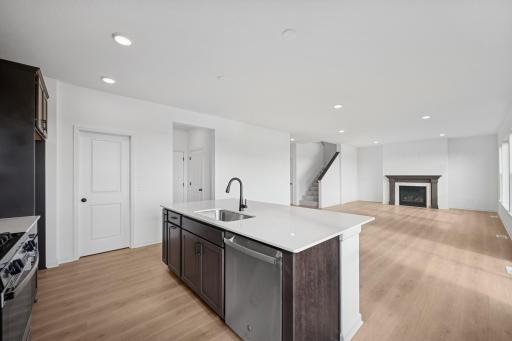 This stylish kitchen features rich cabinetry, quartz countertops, stainless steel appliances, and a large island-perfect for cooking, dining, or entertaining. Home under construction, photo of similar home, selections vary.