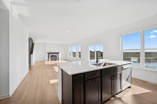 This stylish kitchen features rich cabinetry, quartz countertops, stainless steel appliances, and a large island-perfect for cooking, dining, or entertaining. Home under construction, photo of similar home, selections vary.