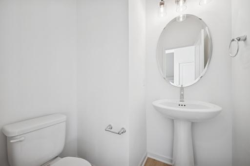 This bright, modern half bath is perfectly located for guests-simple, stylish, and easy to keep tidy. Its clean design makes it a welcoming little retreat on the main level. Home under construction, photo of similar home, selections vary.