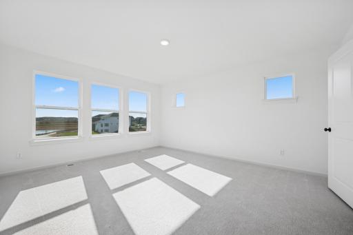 Bright and spacious with large windows and peaceful views, this primary suite offers a relaxing escape. Home under construction, photo of similar home, selections vary.