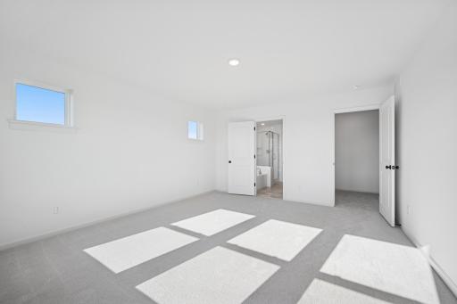 Bright and spacious with large windows and peaceful views, this primary suite offers a relaxing escape. Home under construction, photo of similar home, selections vary.