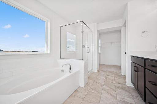 Start and end your day in this spa-like ownerâs bath featuring a soaking tub, walk-in shower, and double vanity. The large window fills the space with light, creating a relaxing atmosphere to unwind after a long day.