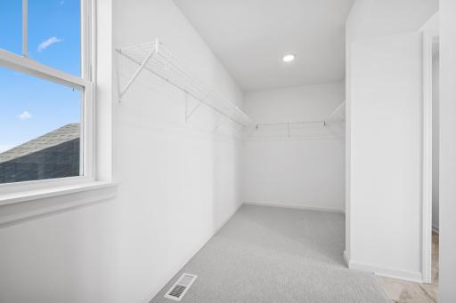 Generous walk-in closet with ample shelving and hanging space, offering both function and luxury just off the primary suite. Home under construction, photo of similar home, selections vary.