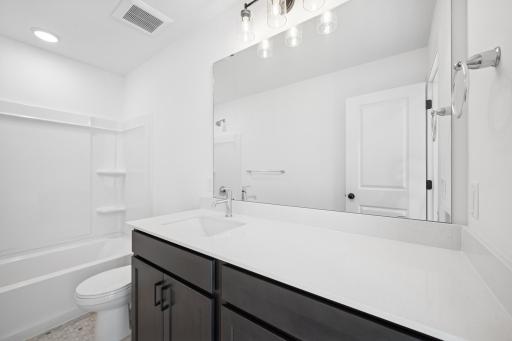 Conveniently located near the additional bedrooms, this full bath offers plenty of counter space and storage, ideal for guests or family members to share comfortably. Home under construction, photo of similar home, selections vary.
