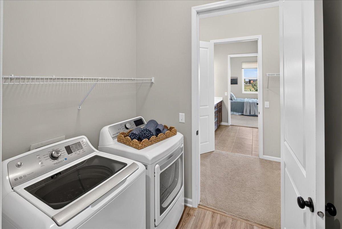 Conveniently located laundry room with washer, dryer, and additional shelving to simplify everyday living.